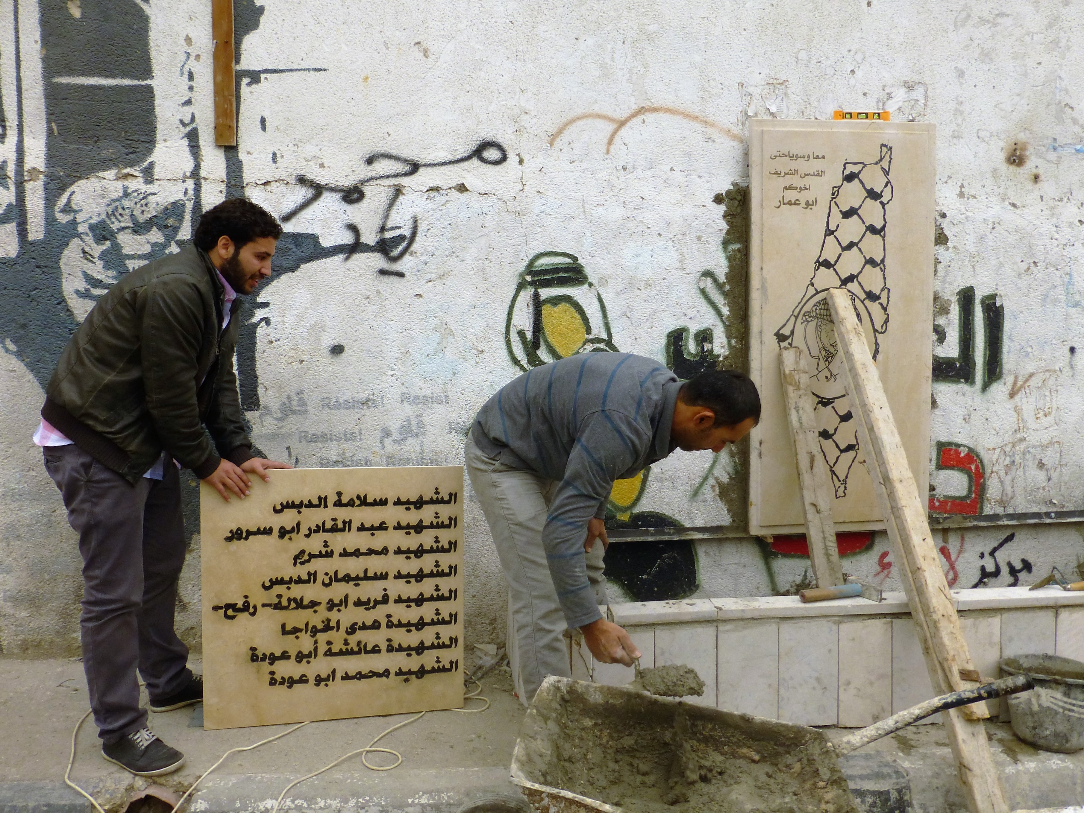 Mohamed y sus compañeros construyendo un nuevo sitio memorial en la entrada al campamento Aida.